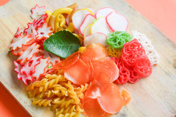Crackers, cuanki, noodles, and complete dry seblak seasoning on a wooden tray