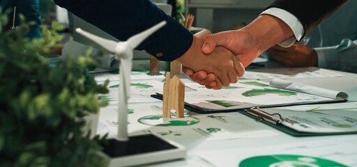 Two business professionals engaging in a firm handshake to seal a deal for an eco-friendly project...