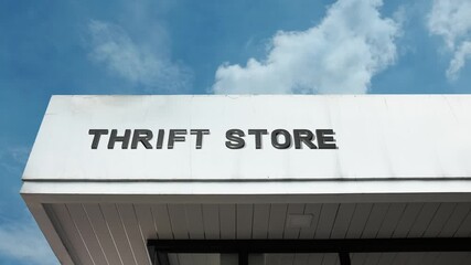 Thrift Store word sign displayed on a commercial or retail building under a clear blue sky, symbolizing secondhand goods, affordability, vintage retail, sustainability, community charity, and bargain