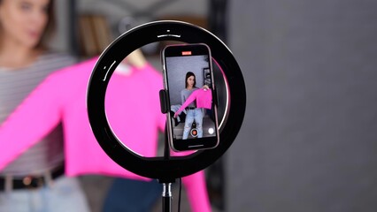 Smartphone screen during video recording by female video blogger. Happy young woman showing pink jumper to followers. video. Vlogging concept