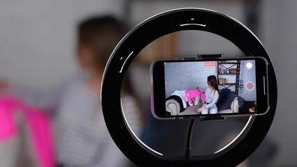 Female vlogger using mobile phone while recording video for sell clothes, selling online. Lady showing jumper at home office. Small business owner, online market concept