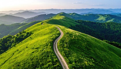 Winding Dirt Path Through Lush Green Rolling Hills Under a Soft Golden Hour Sky with Hazy Distant Mountains