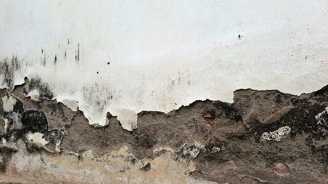Weathered concrete wall grunge background with peeling paint, aged cracks, surface damage and moisture spots