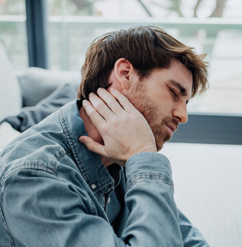 Upset tired young man feeling pain massaging stiff neck rubbing tensed muscles to relieve back ache joint shoulder discomfort after long sedentary work in incorrect posture, fibromyalgia concept