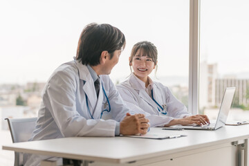 Obraz premium A male supervising doctor and a female trainee doctor are receiving training while looking at electronic medical records on a computer 