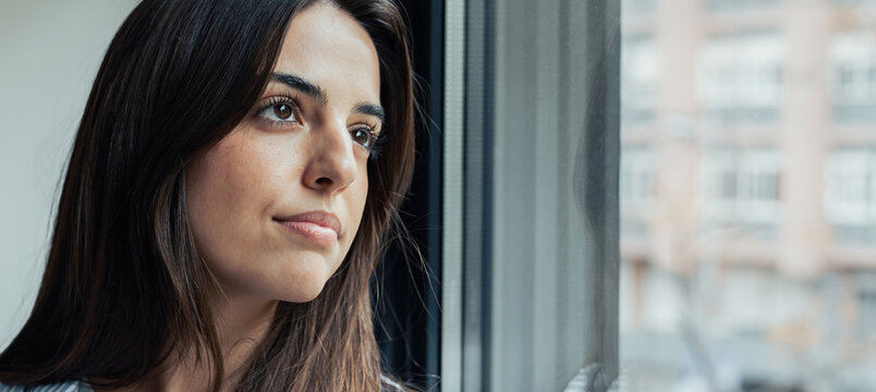 Unhappy thoughts. Worried young caucasian woman look at window feel lonely sad wait for boyfriend husband coming back after quarrel. Pessimistic millennial lady hide from life problems at home. 