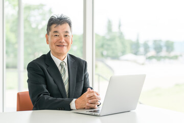 Senior Asian male businessman in a suit sitting at a desk
