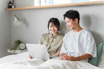 Obraz premium Asian couple, couple, lover, family using laptop in bedroom 