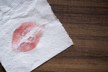 servilleta de papel blanca con mancha de lápiz labial rojo sobre mesa de madera