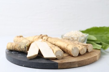 Roots, cut and grated horseradish on white table, closeup
