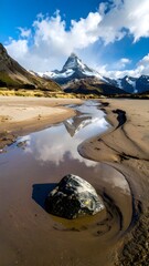Iconic snow-capped mountain peak reflecting perfectly in a winding stream flowing through a remote, beautiful valley