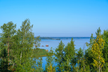 Lake view through green and yellow trees on a sunny autumn morning