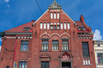 Historic red brick building with ornate facade under blue sky