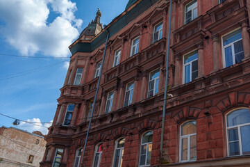 Tall historic red brick building with decorative roof under blue sky