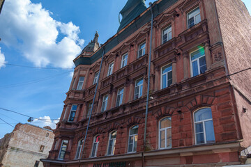 Tall historic red brick building with decorative roof under blue sky