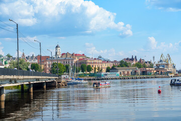 Obraz premium Historic waterfront cityscape with bridge and boats on a calm summer day