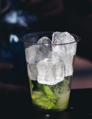 Barman mixing liquor beverages and alcohol drinks in plastic cups, bartender working, beautiful row line of different coloured cocktails on open air summer party in a bar, catering on banquet event