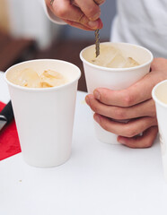 Barman mixing liquor beverages and alcohol drinks in plastic cups, bartender working, beautiful row line of different coloured cocktails on open air summer party in a bar, catering on banquet event