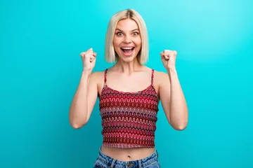 Fotobehang Muziek Young woman with a joyful expression wearing a patterned tank top stands against a bright turquoise background  © deagreez