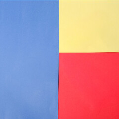 Minimalist composition featuring blue, yellow, and red paper sheets arranged in a clean geometric grid, forming bold primary color blocks with sharp, defined edges and balance.