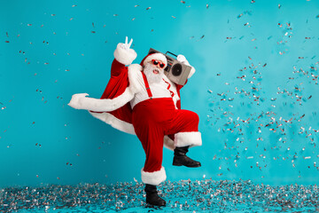 Santa dances with a boombox as confetti falls in blue studio celebrating Christmas and the holiday season fun energy Christmas dream