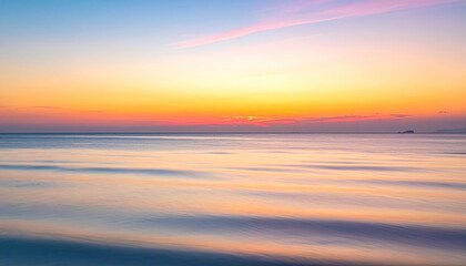 Vibrant sunset over calm ocean waters with soft clouds reflecting pastel colors in a serene coastal panorama