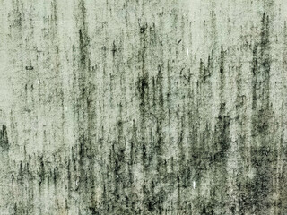 A weathered wall surface displays vertical streaks of dark grime and discoloration against a light background. 