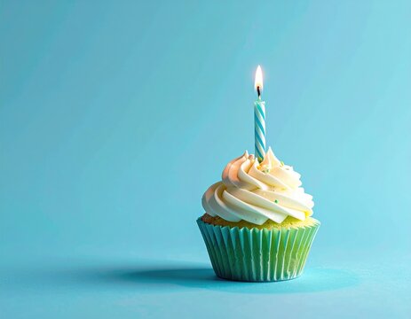Cupcake with lit candle on blue background