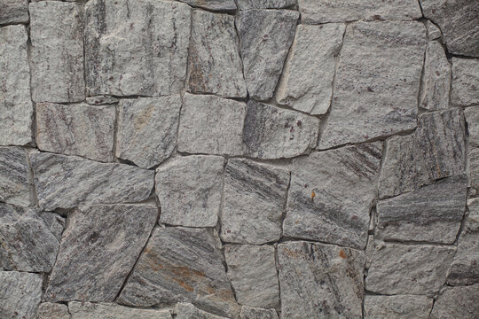 Grey natural stone wall texture: Rustic facade cladding background