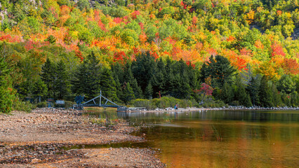 Autumn scenes at Jordan Pond with rocks at foreground and forest at background