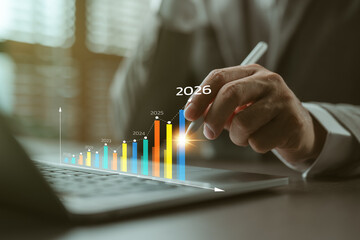 Hand holding pen pointing at rising business graph with yearly growth from 2020 to 2026,...