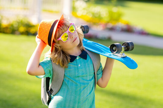 Happy stylish child in sunglasses and fashion summer hat posing with skateboard outdoor. Concept of activity and happy childhood. - Powered by Adobe