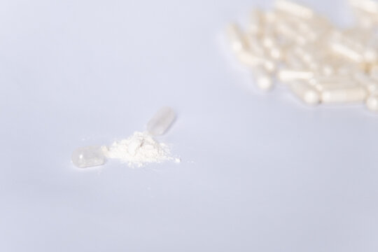 Open capsule with lactobacilli on the background of many capsules on a white background. Probiotics for the intestines.