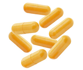 group of bright orange or yellow nutritional capsules scattered randomly, likely containing vitamins or supplements, isolated against a black backdrop.