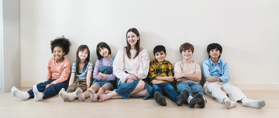 Portrait of teacher and group of multicultural students sit in classroom, asian caucasian children together in school. Home school education, diversity multicultural community. Back to school