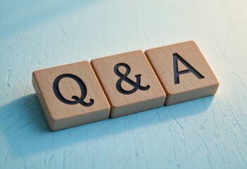 Q and A letters on wooden blocks, light blue textured surface background, close up of question answer communication icon.