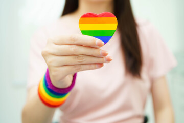 Asian woman holding LGBT heart with rainbow flag.