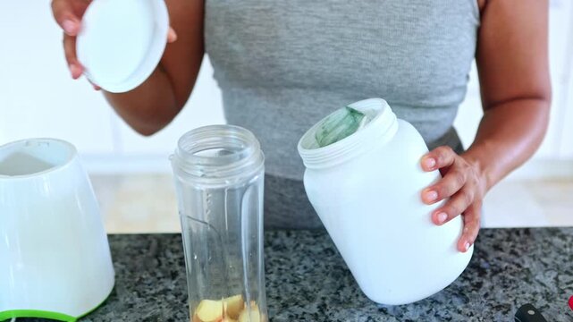 Tattooed woman opening protein powder jar in the kitchen