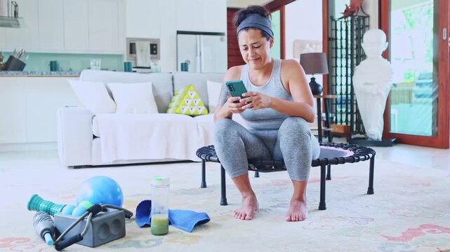 Mature woman checking social media after a workout at home