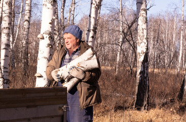 man in jacket carries pile of firewood for winter. Cold winter, natural heating. Cold winter period.
