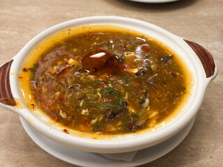 A direct overhead close-up shot of a bowl of thick, dark-colored, savory Asian soup, strongly resembling Hot and Sour Soup or a similar rich, spicy broth