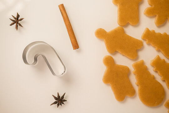 Bakery background. On a white table the dough is rolled out on which gingerbread cookies in the form of snowflakes, a snowman, and a gingerbread man are squeezed out using molds. Christmas baking.