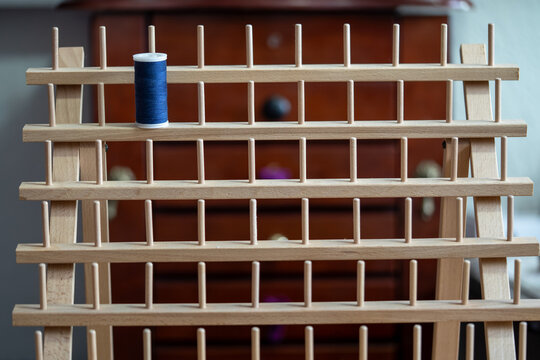 porta hilos de madera con un carrete de hilo azul y fondo de cajonera