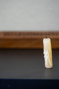 una vela apagada con cera escurrida seca con fondo de caja para incienso desenfocada sobre mesa de madera caf&eacute;