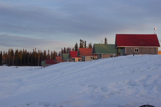 Row of houses on a hill in Fairbanks, Alaska. Red and green roofs on a snowy hill in the pine forest. Winter wonderland - Powered by Adobe