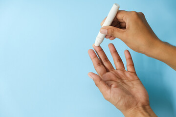 World diabetes day and blue ribbon awareness with red blood drop in woman hands isolated on a blue background. World diabetes day,14 november. Copy space. Top view