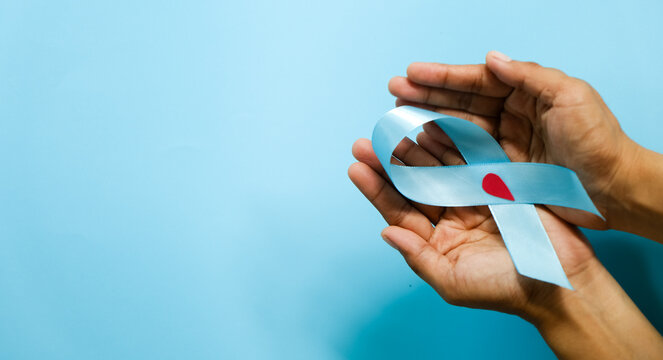 World diabetes day and blue ribbon awareness with red blood drop in woman hands isolated on a blue background. World diabetes day,14 november. Copy space. Top view