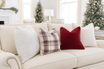 Fototapeta premium Cozy christmas sofa with festive pillows and decorated trees in the background