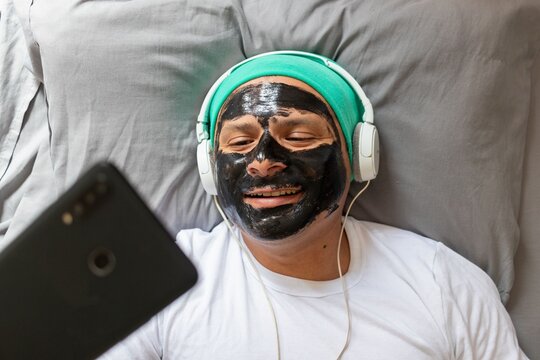 Man with headphones and a face mask takes a selfie