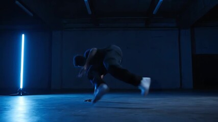 Man Dancing in Dark Studio with Blue Neon Light Artistic Performance
